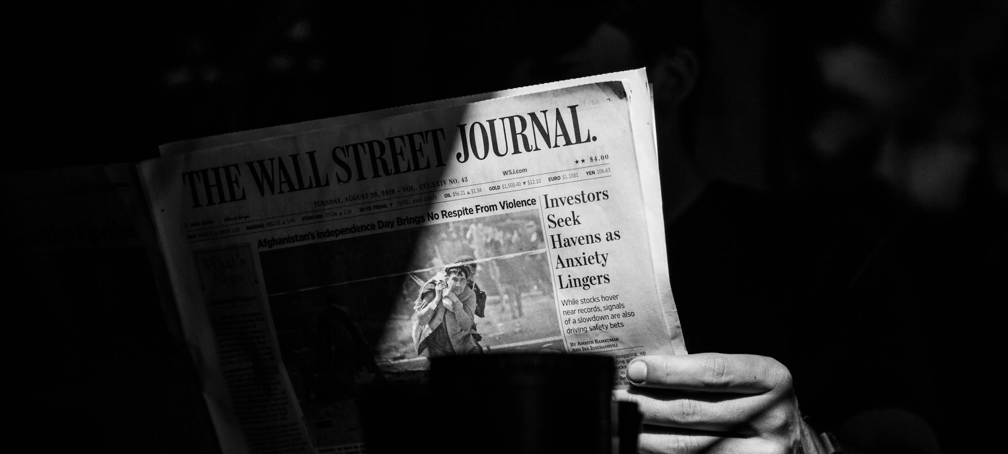 A monochrome photograph capturing a person reading The Wall Street Journal.